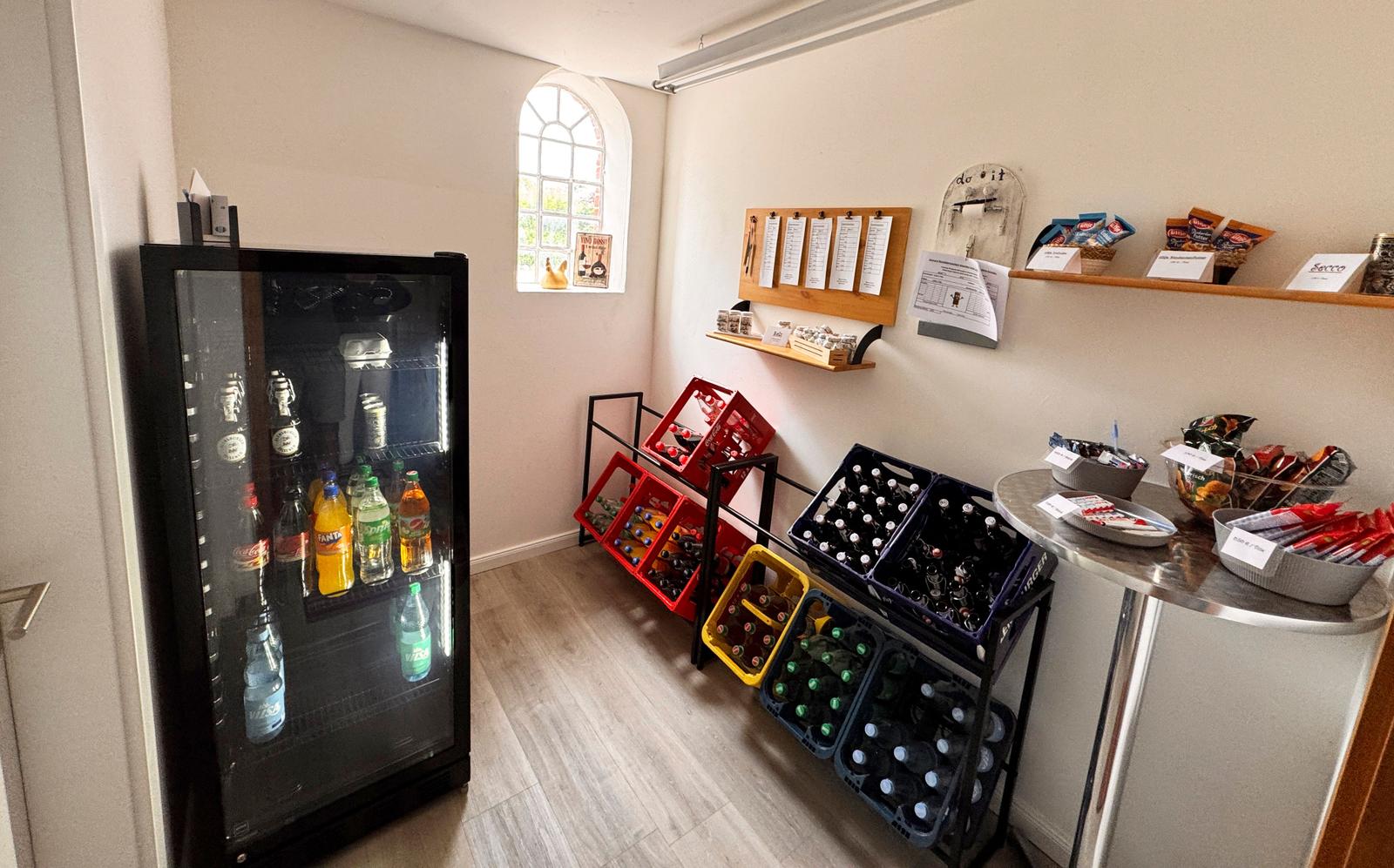 Kühlschrank mit Getränken, Flaschenregale und Snacktische in der Lounge.