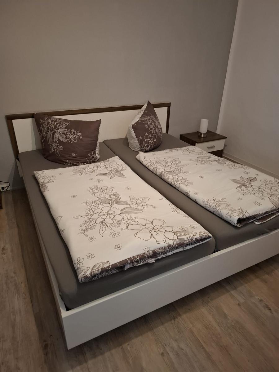 Schlafzimmer mit Doppelbett, Bettwäsche mit Blumenmuster und Nachttisch.