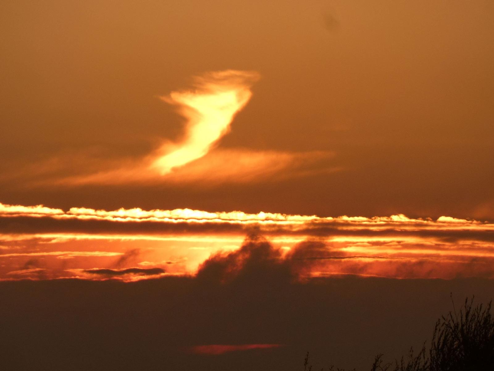 Sonnenuntergang mit orangefarbenen Wolkenformationen am Horizont.