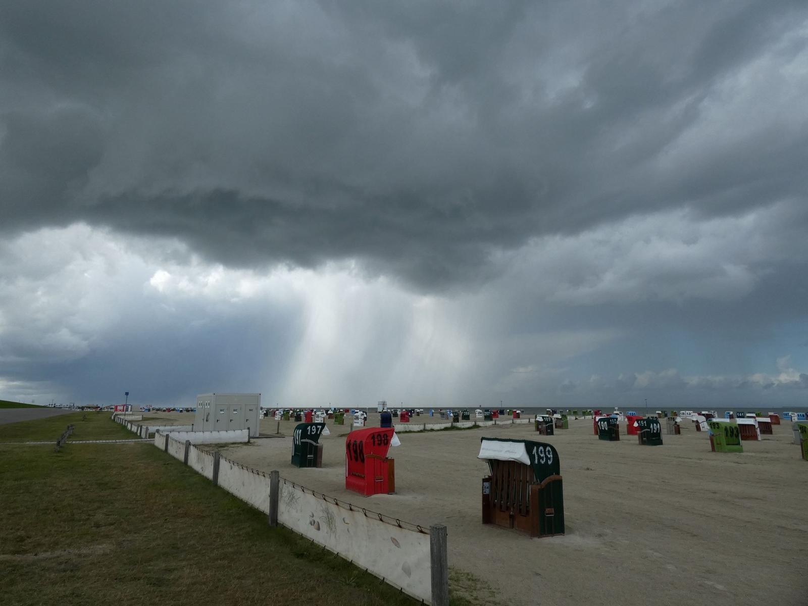 Strand mit bunten Strandkörben unter stürmischen Himmel.