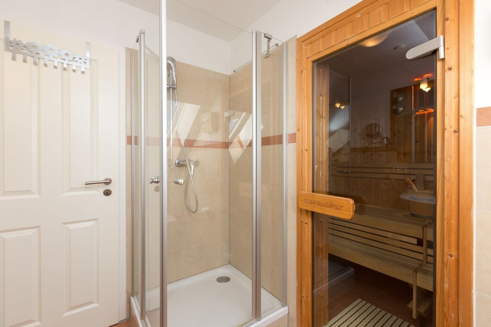 Dusche mit Glaswand und Sauna mit Holzbank