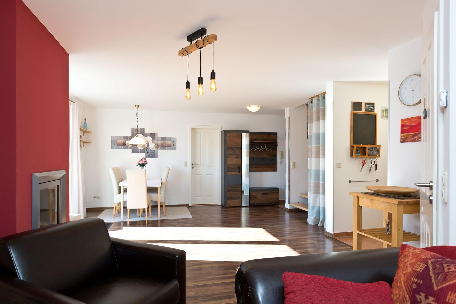 Wohn- und Essbereich mit Holzboden, Sofa, Tisch und Lampen.