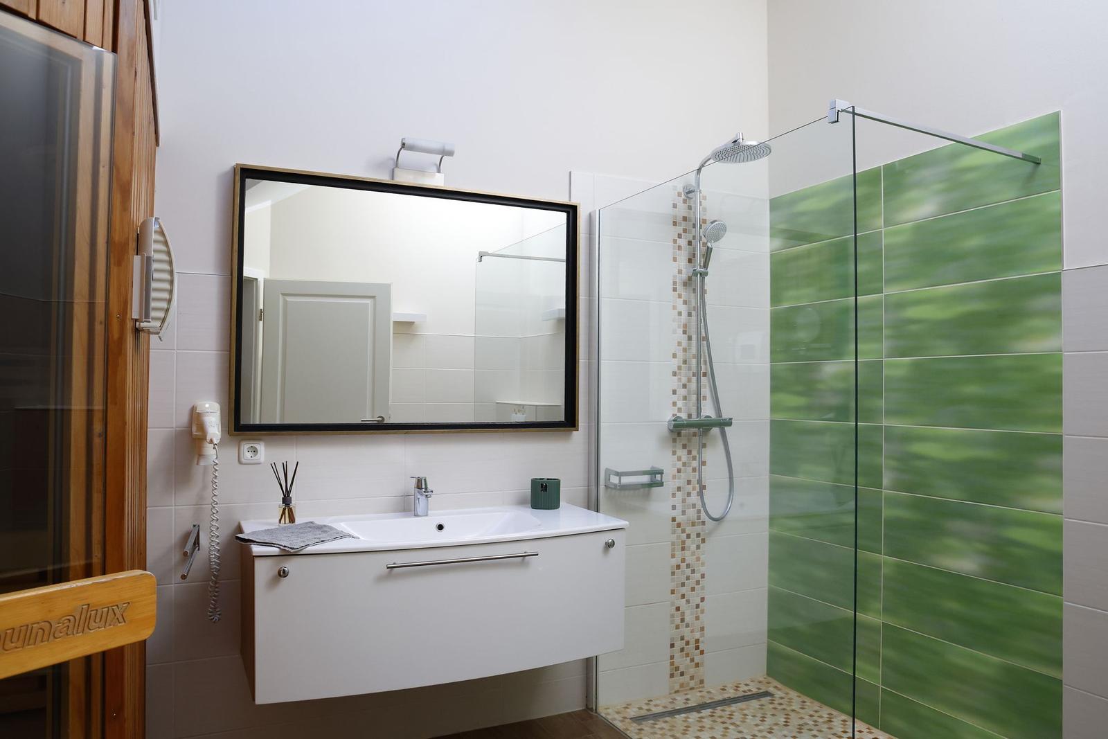 Badezimmer mit Dusche, Waschbecken und Spiegel.
