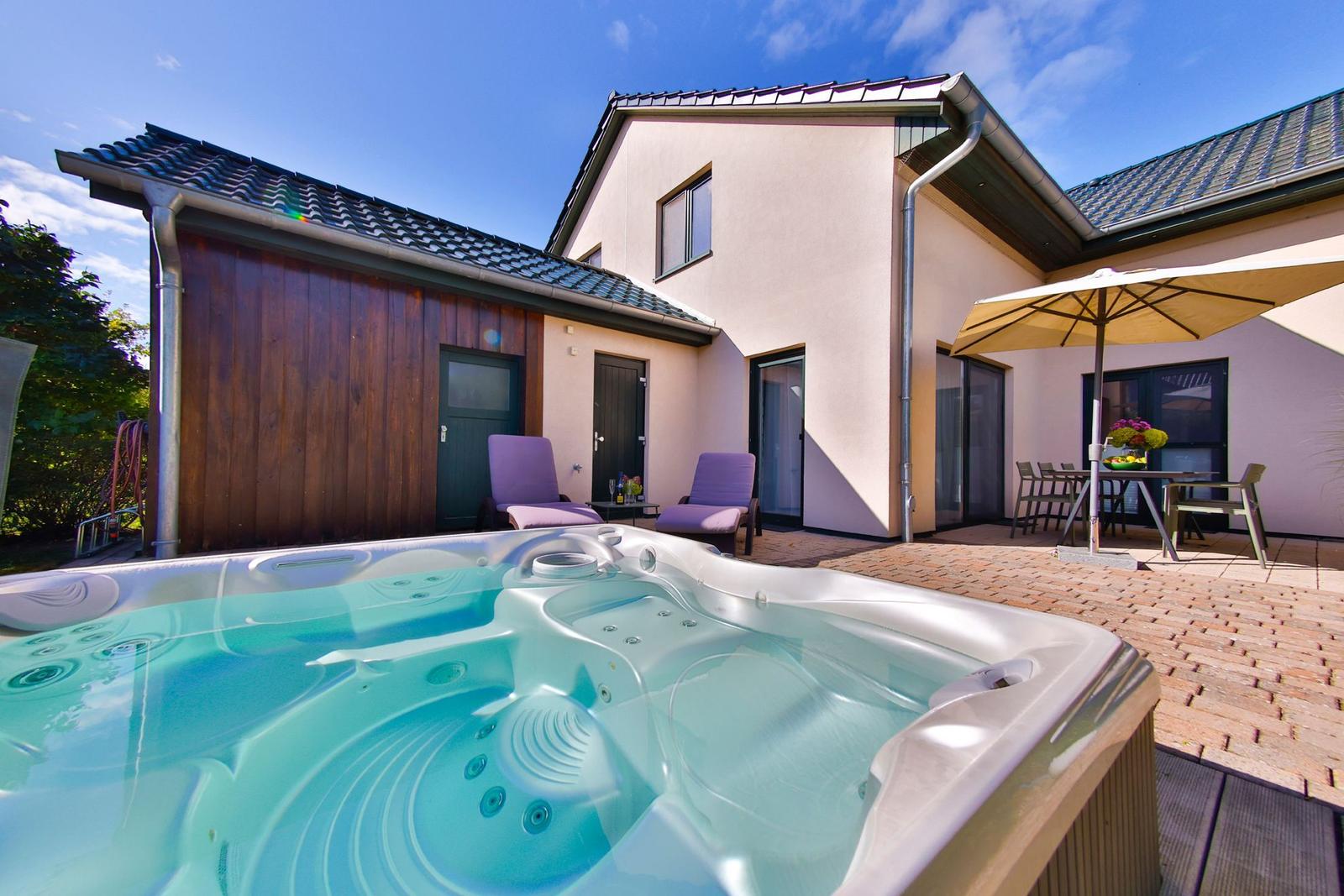 Haus mit Whirlpool, Terrasse und Sitzgelegenheiten unter einem Sonnenschutz.