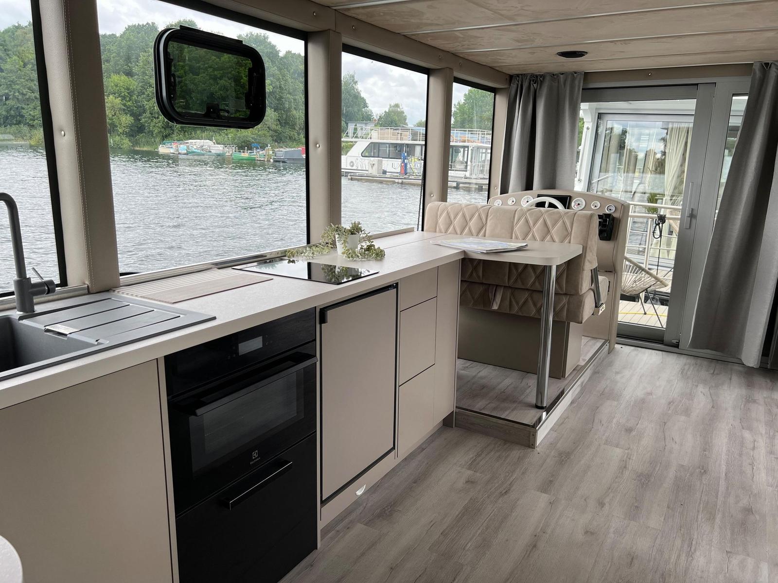 Küche mit Fenstern zum Wasser und Steuerstand mit Ledersitz.