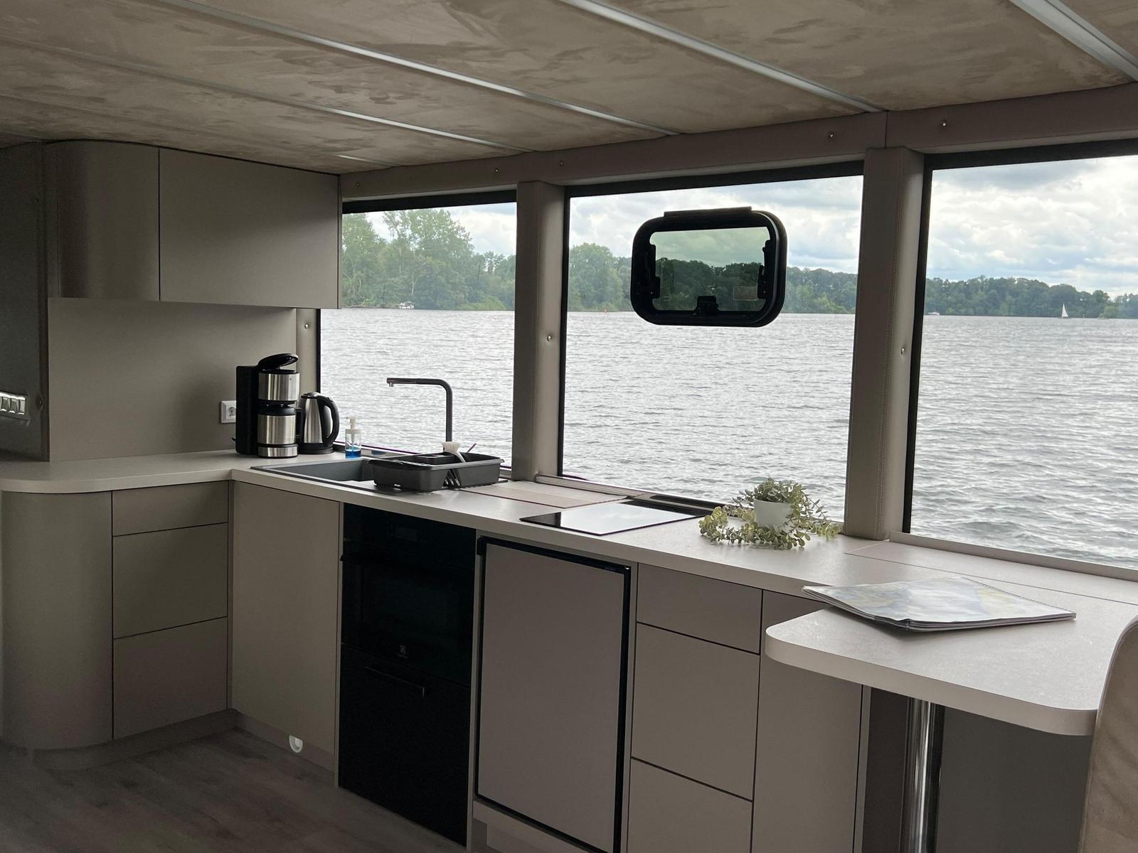 Küche mit Blick auf Wasser und Ufer. Geräte und Arbeitsfläche sichtbar.