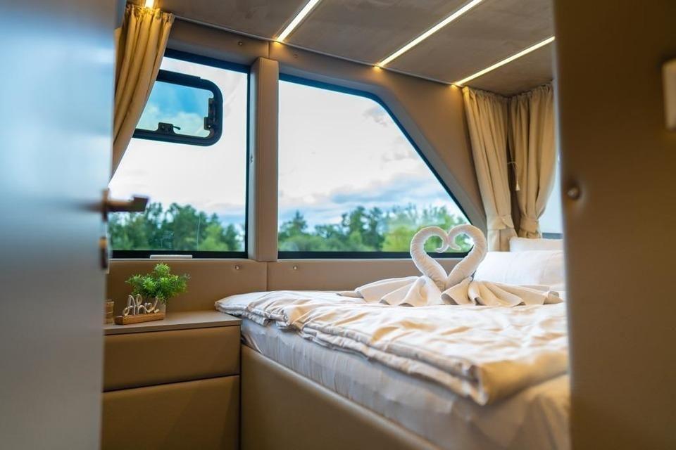 Schlafzimmer mit Bett, Fenster und Handtuchschwanen