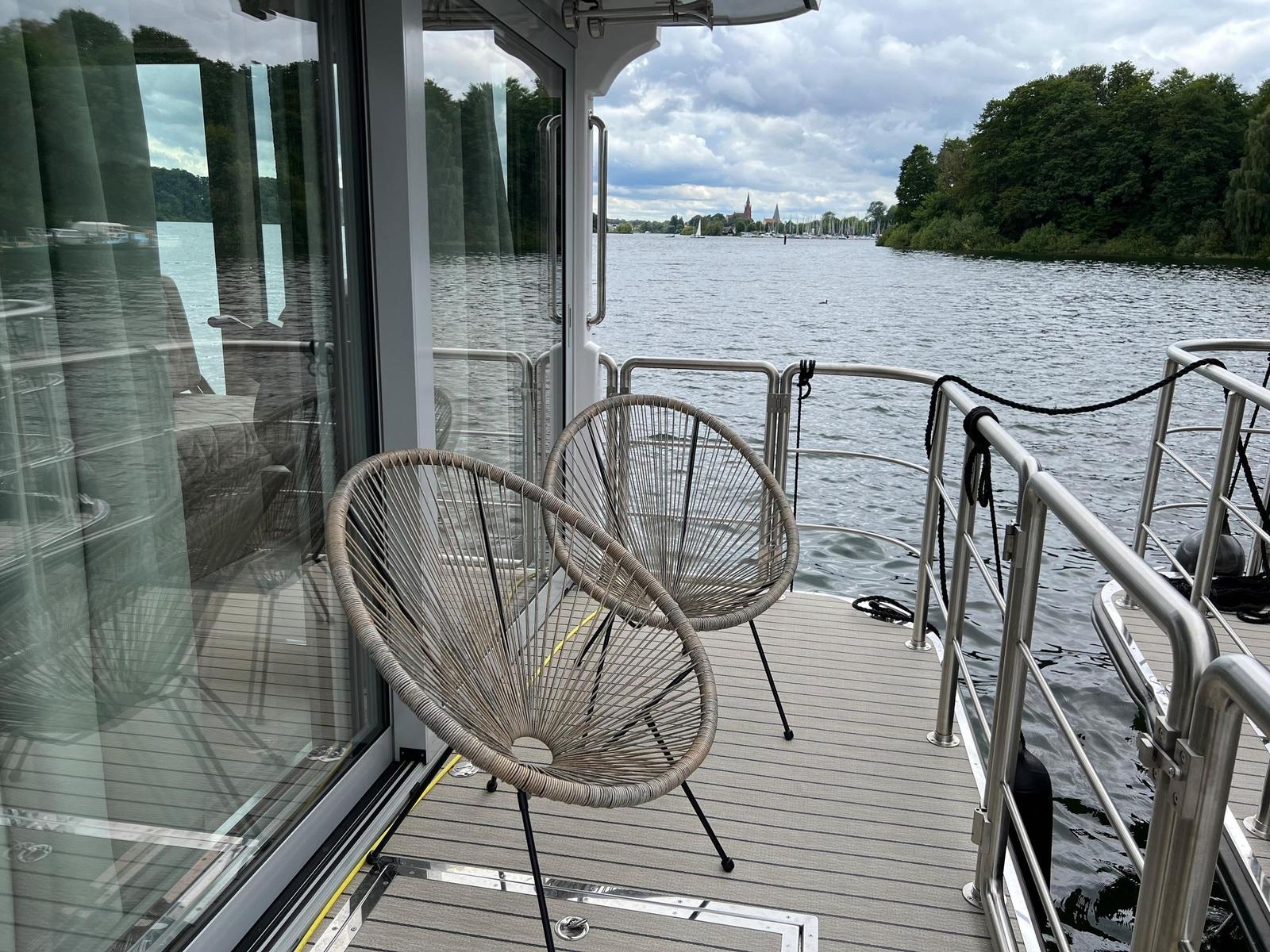 Terrasse mit zwei Stühlen und Blick auf Wasser und Ufer.