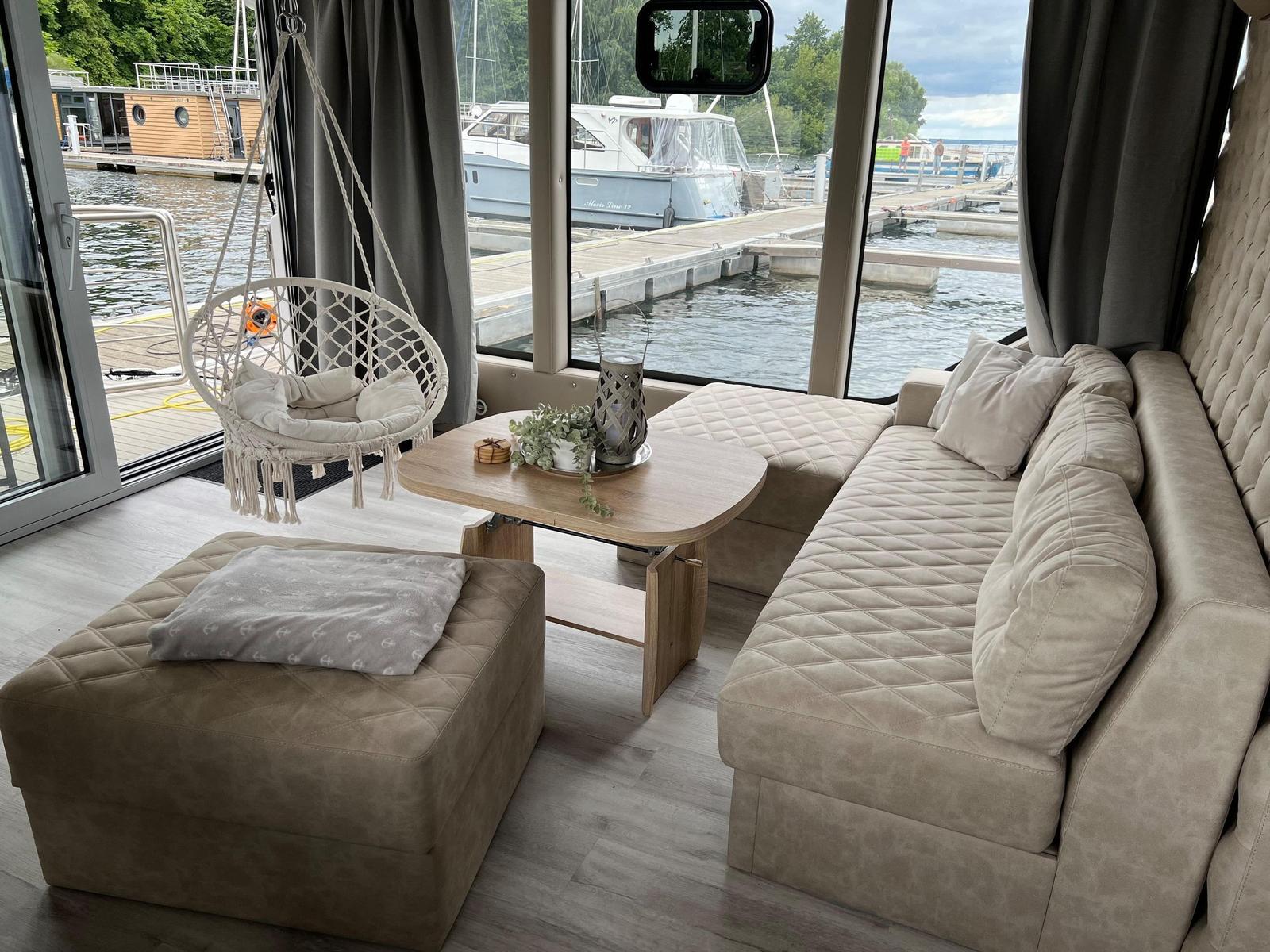 Wohnbereich mit Sofa, Hängesessel und Blick auf den Hafen.