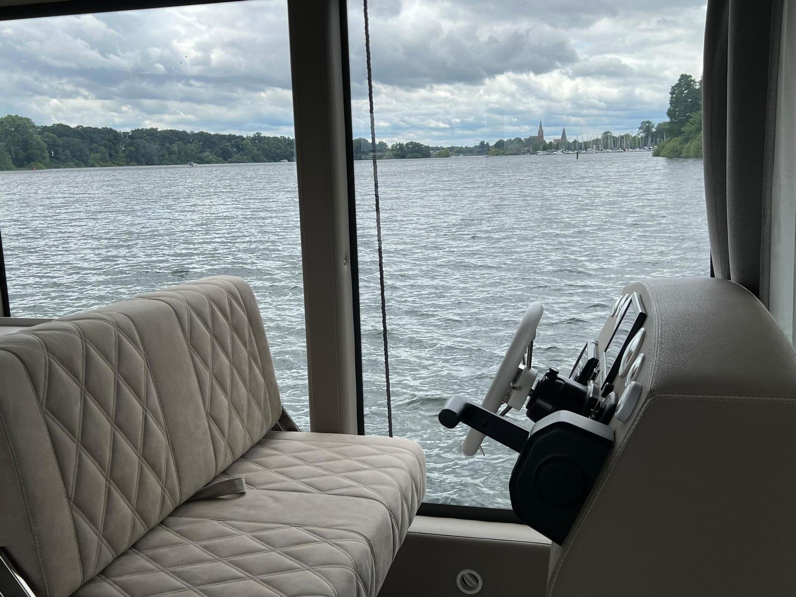 Sitzbereich mit Steuerung und Blick auf Wasser und Ufer.