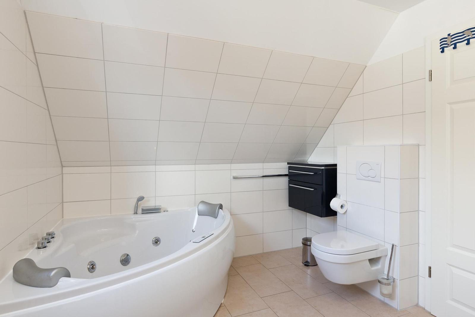 Dusche mit Badewanne, Toilette und schwarzer Schrankwand.