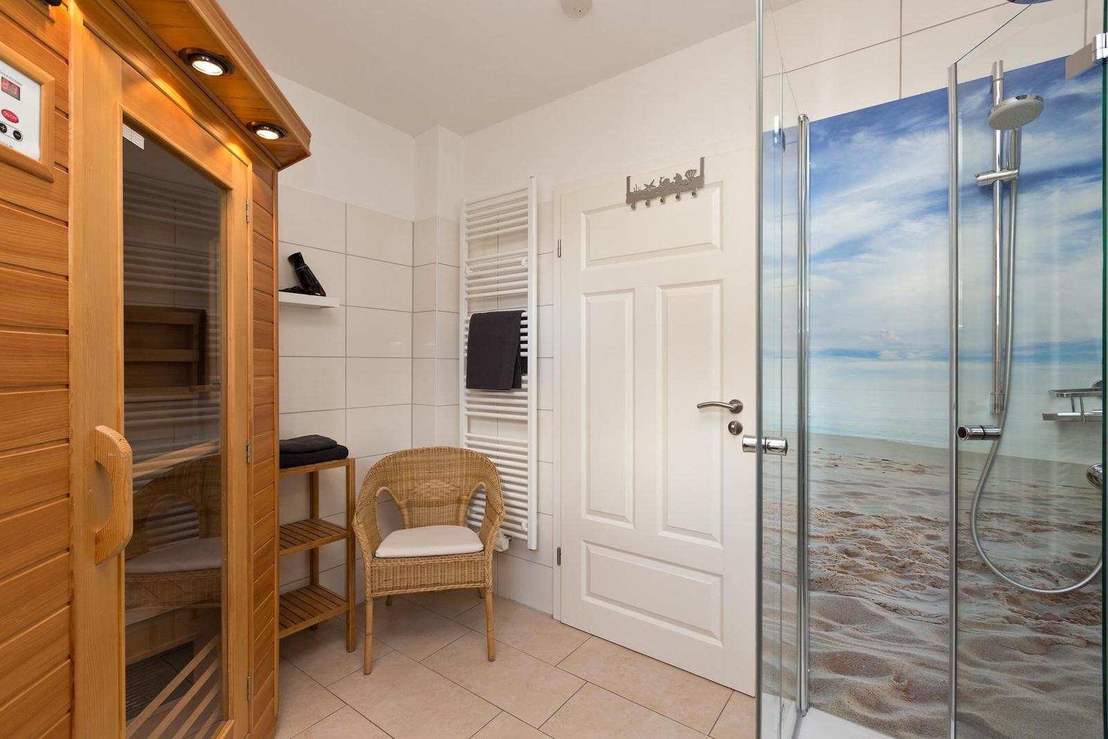 Dusche mit Strandmotiv, Sauna und Wickerstuhl im Badezimmer.