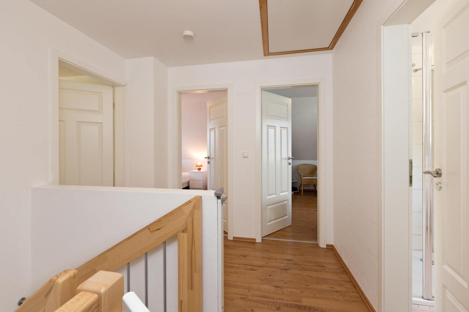 Flur mit Holzboden und Türen zu Schlafzimmer und Bad.