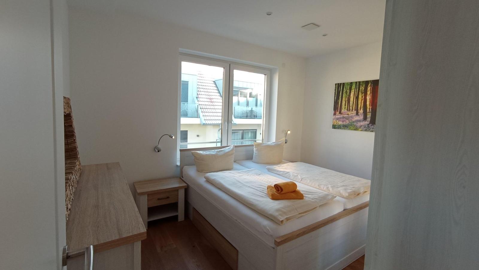 Schlafzimmer mit Doppelbett, Fenster und Wandbild.