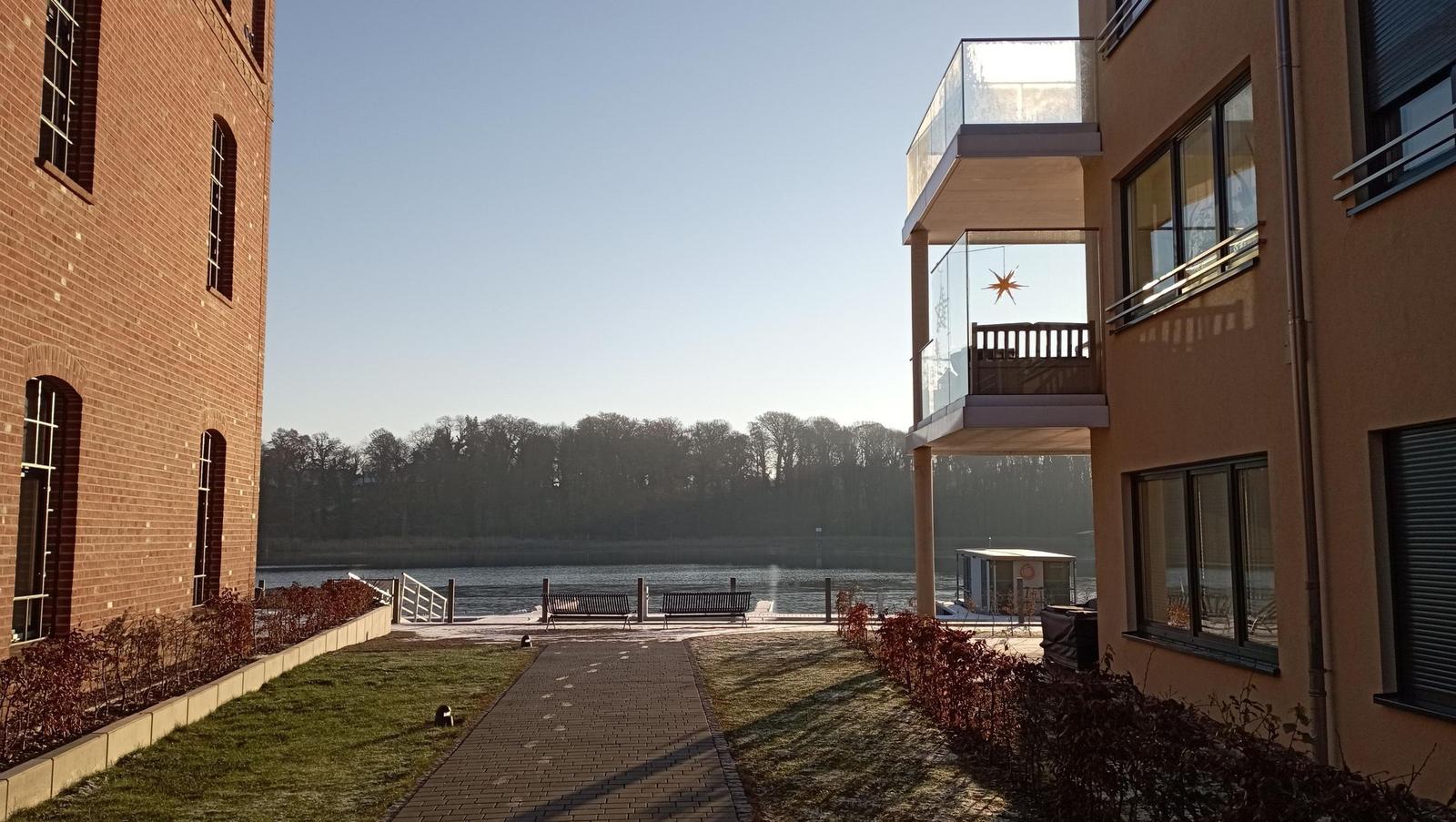 Wohnung mit Balkon, Blick auf Fluss und Uferweg mit Bänken.