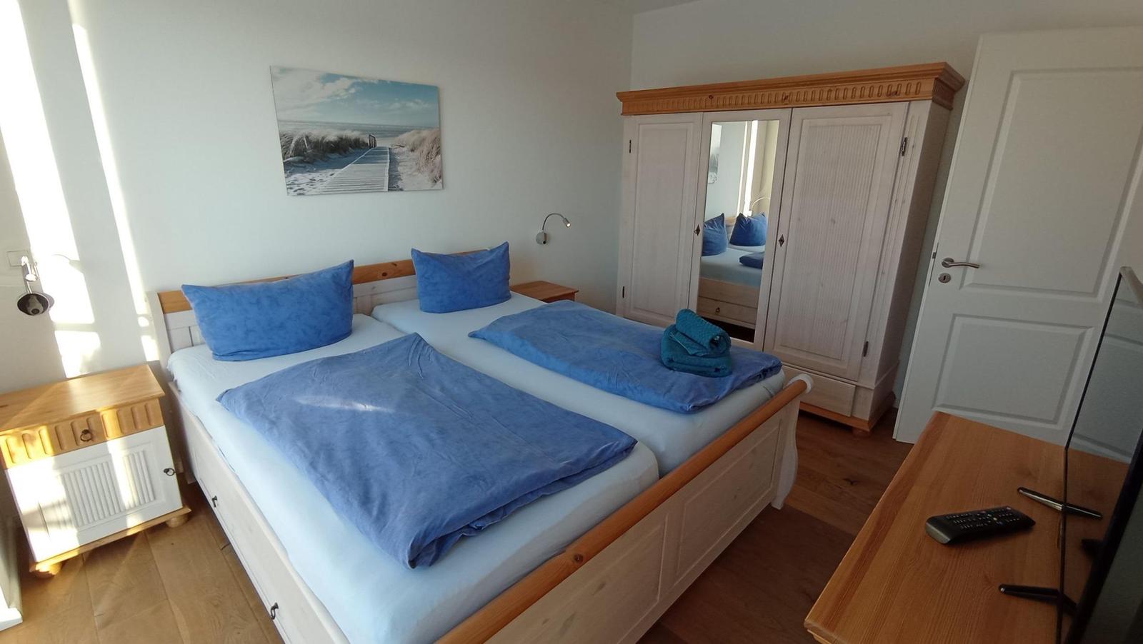 Schlafzimmer mit Doppelbett, Kleiderschrank und Wandbild