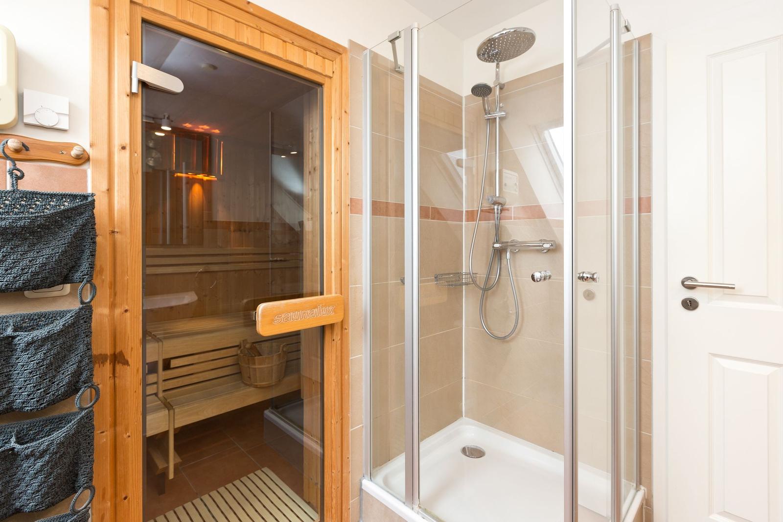 Dusche mit Duschbrause und Sauna mit Holzbank.