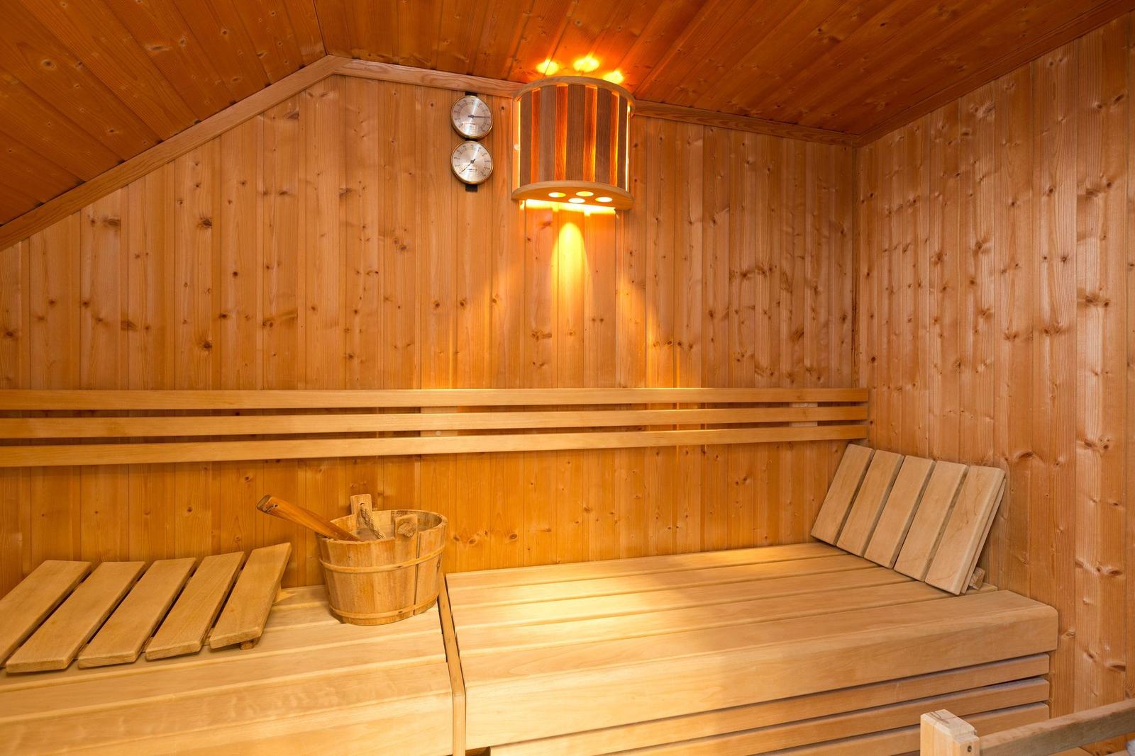 Sauna mit Holzbank, Holzschale und Wandthermometer.