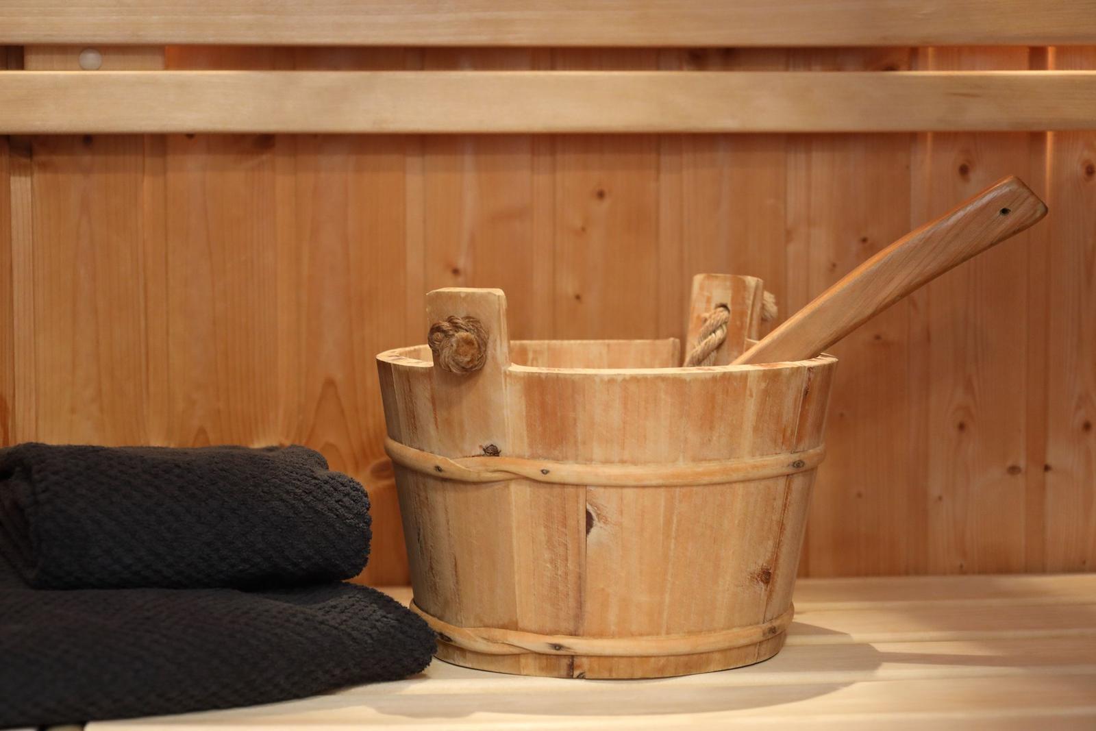 Holzbadewanne mit Besen und Handtuch in Sauna