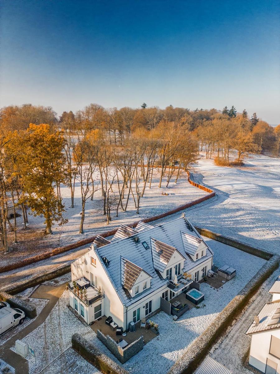 Wohnhaus mit Schneebedecktem Dach und Gartenbereich in winterlicher Umgebung.