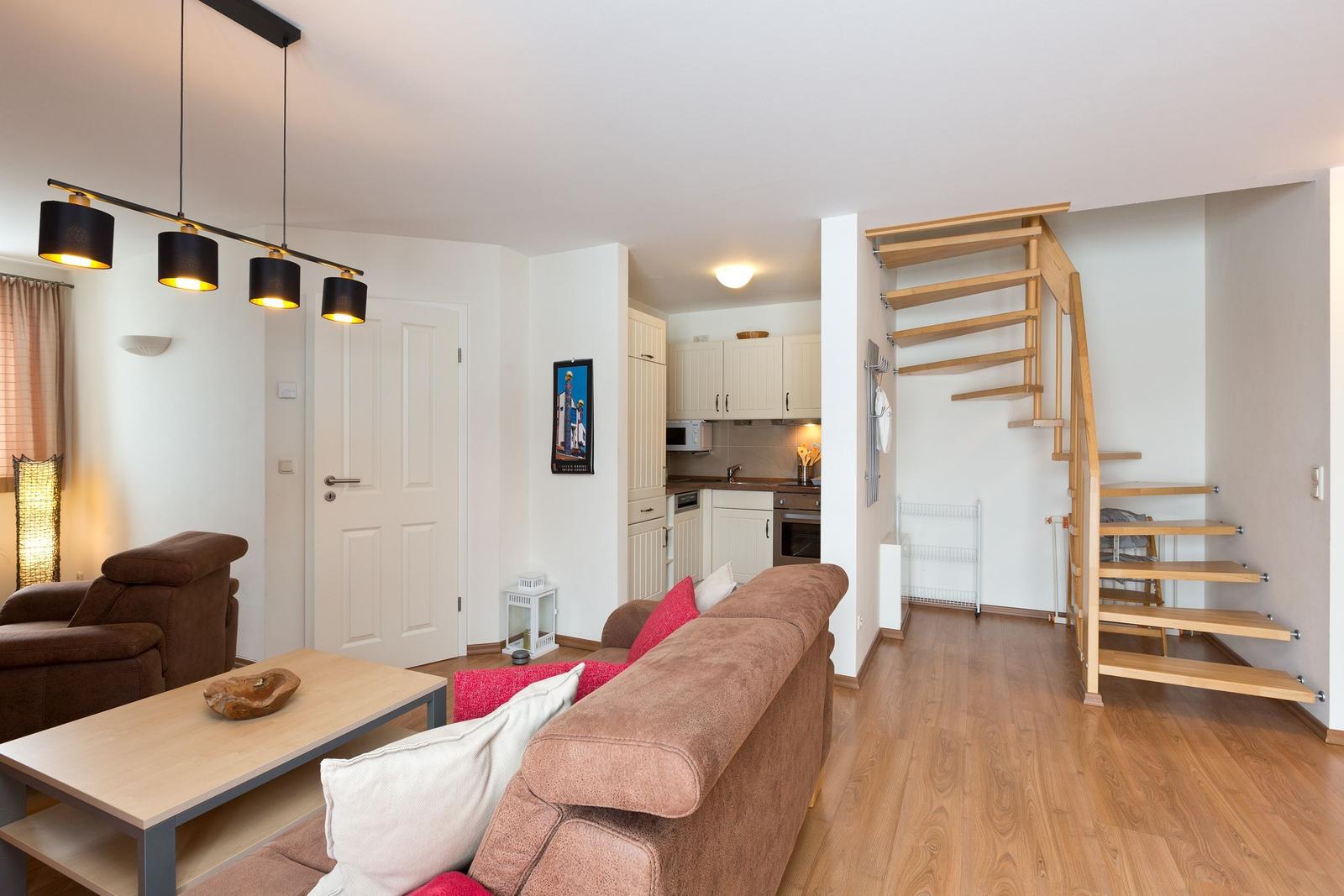 Wohnung mit Wohnzimmer, Küche und Holztreppe zur oberen Etage.