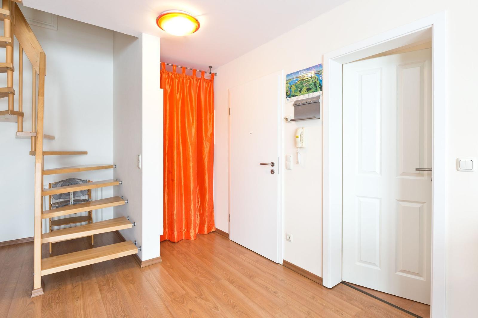 Haus mit Holztreppe, orangefarbener Vorhang und weißen Türen.