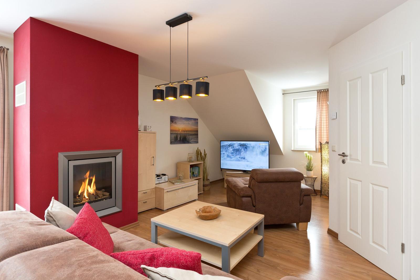 Wohnzimmer mit Kamin, Sofa, Fernseher und Holzboden.