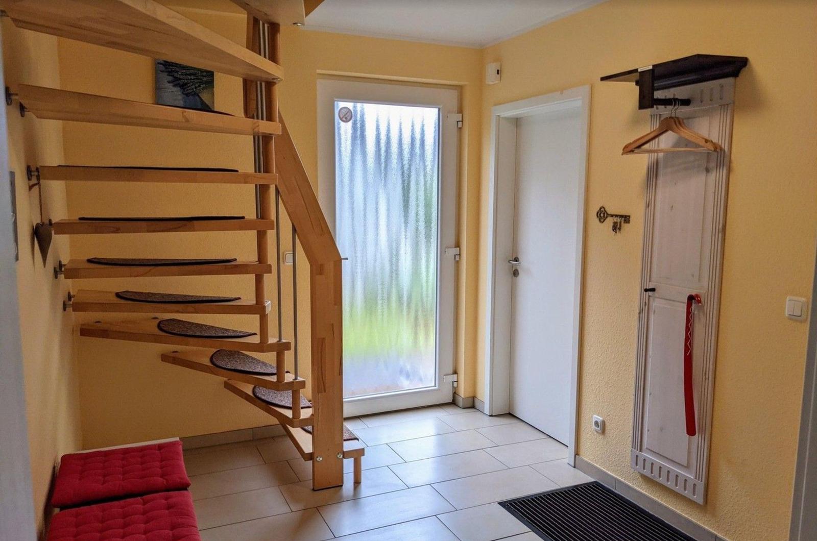 Hausflur mit Holztreppe, Glastür und Kleiderständer