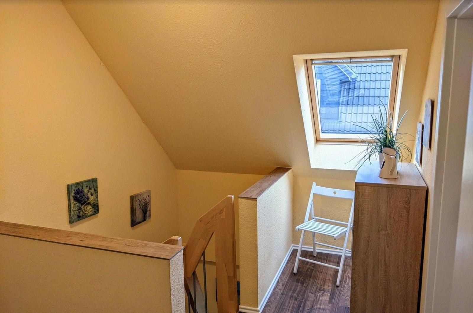 Haus mit Treppe, Dachfenster und kleiner Sitzgelegenheit