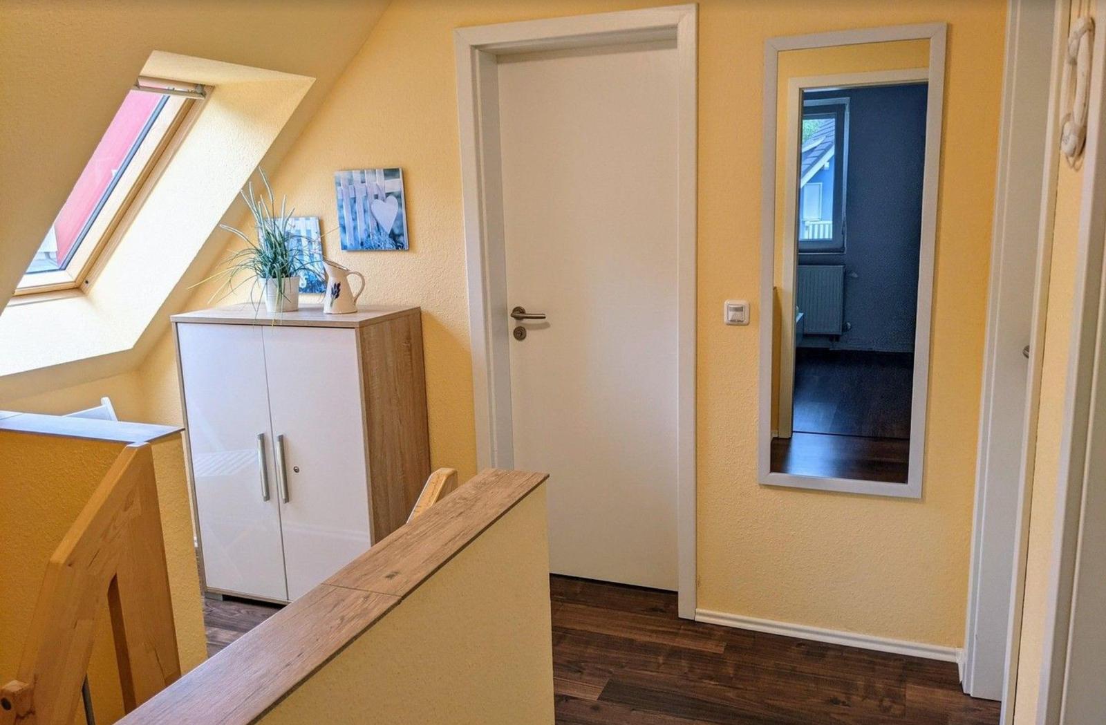 Dachgeschoss mit Dachfenster, Schrank und Spiegel an der Wand.