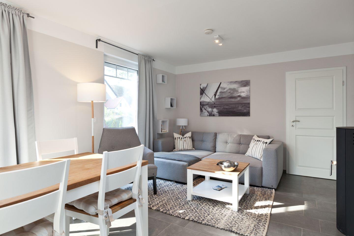 Wohn- und Essbereich mit Sofa, Tisch und Stühlen. Wandbild und Fenster sichtbar.