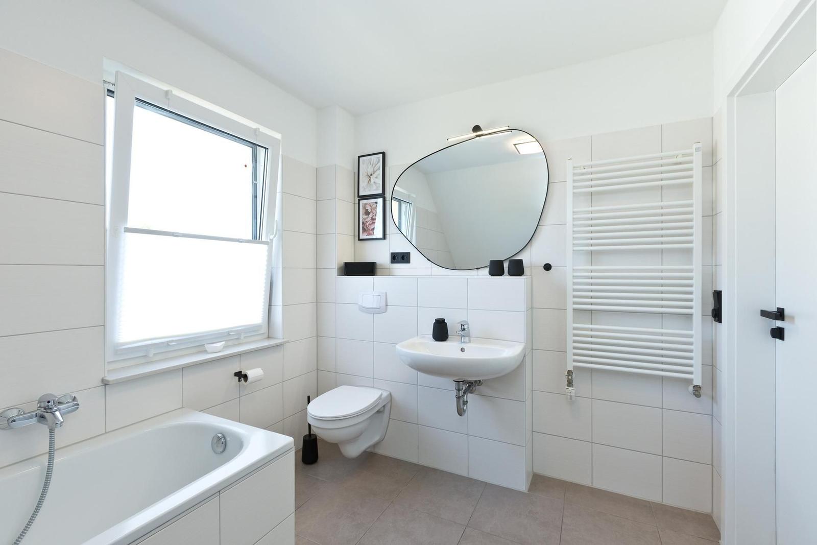 Badezimmer mit Badewanne, Waschbecken, Toilette und Heizkörper.