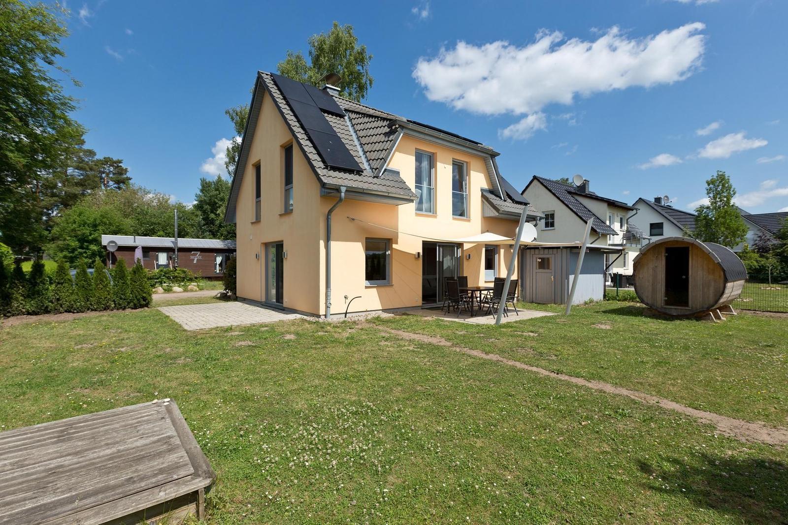 Haus mit Garten, Terrasse und Holzsauna. Solaranlage auf Dach.