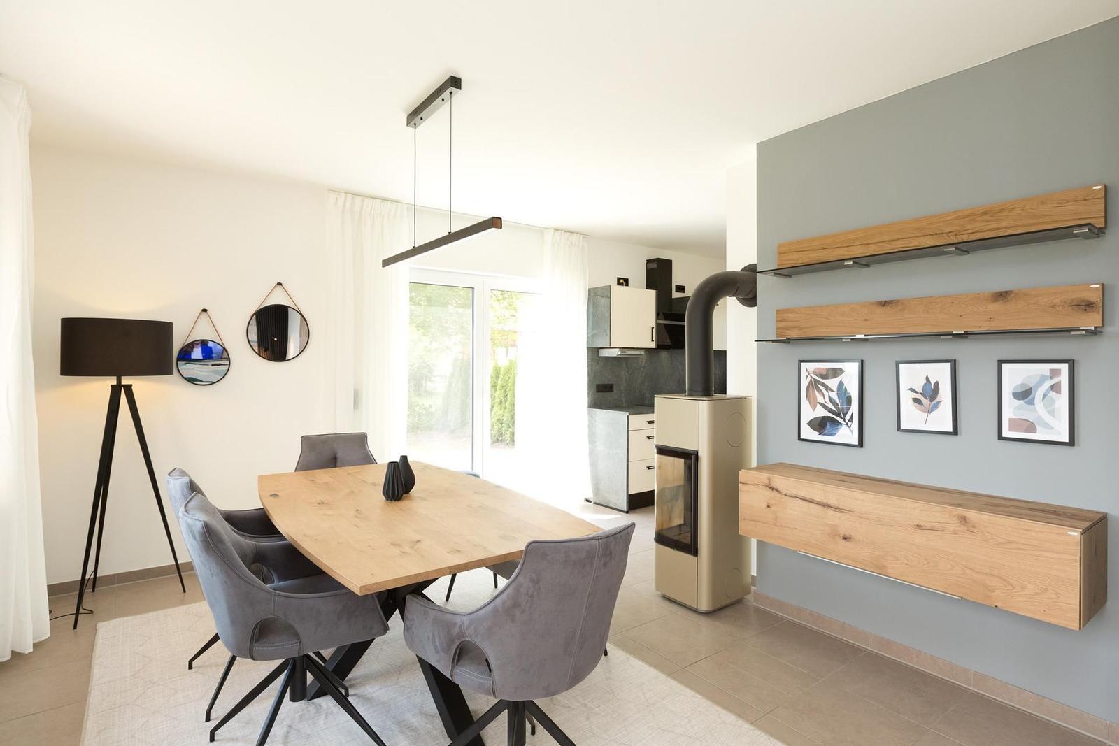 Essbereich mit Holztisch, grauen Stühlen und moderner Einbauküche.