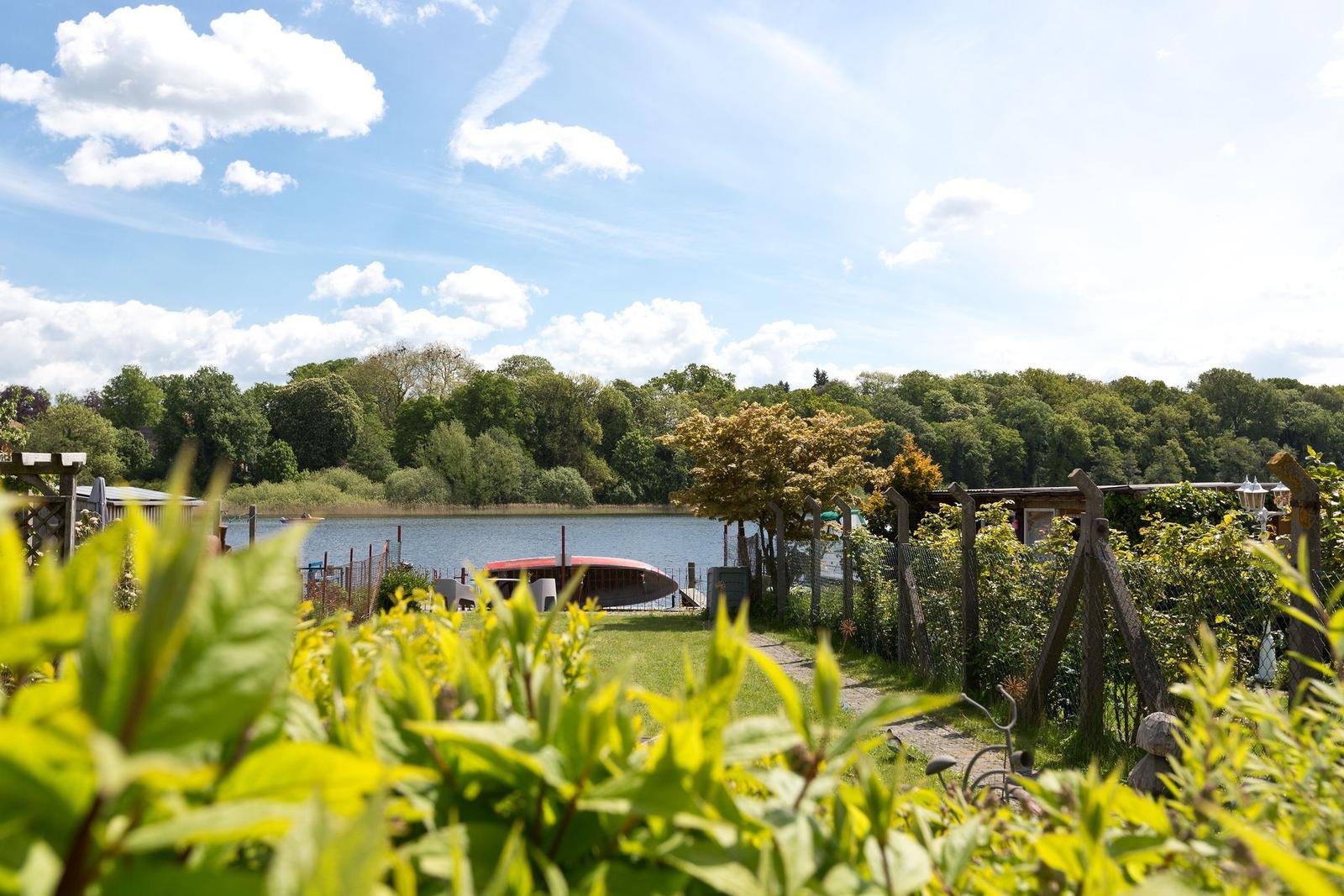 Garten mit Blick auf einen See und grüne Bäume im Hintergrund.