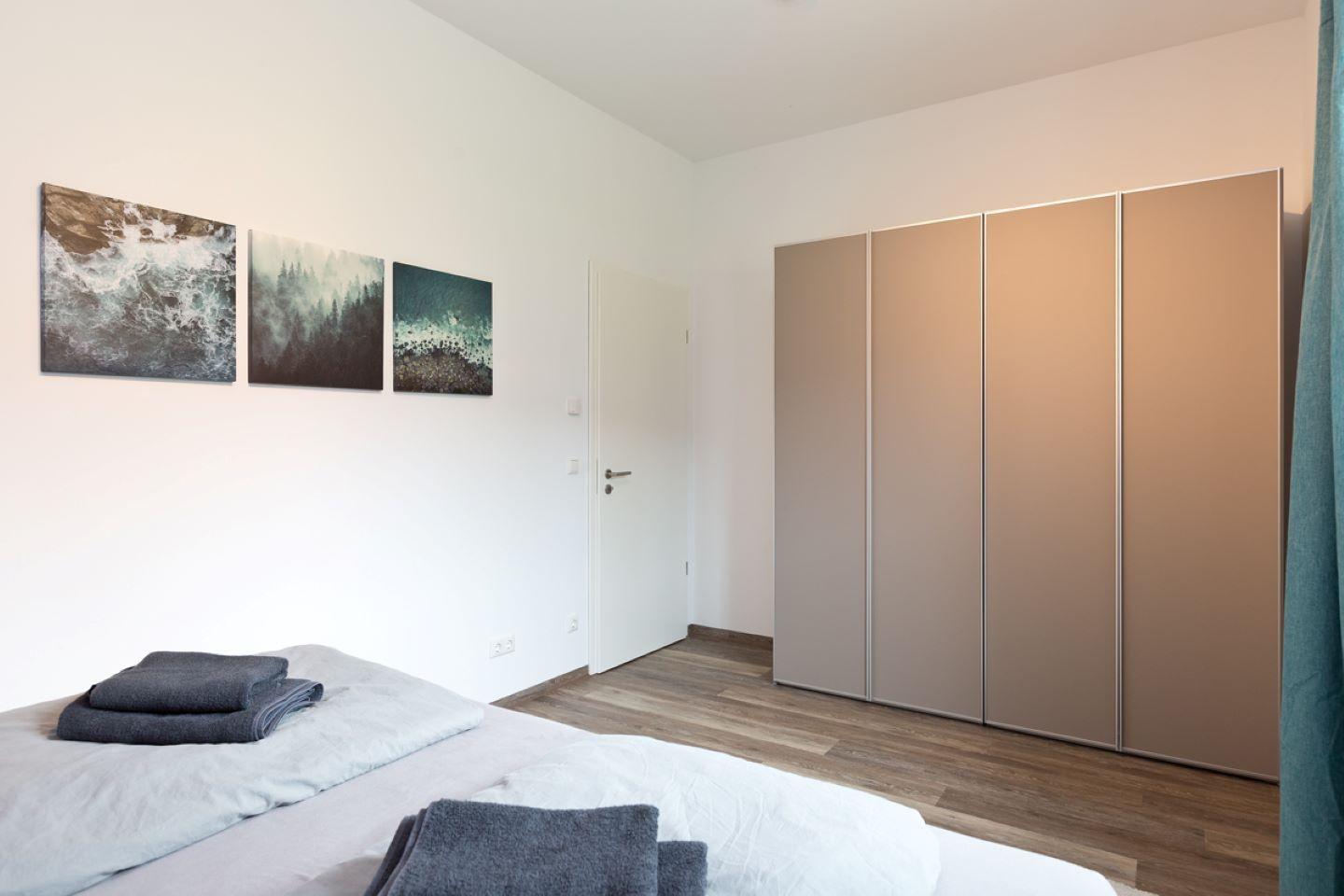 Schlafzimmer mit Bett, Kleiderschrank und Wandbildern
