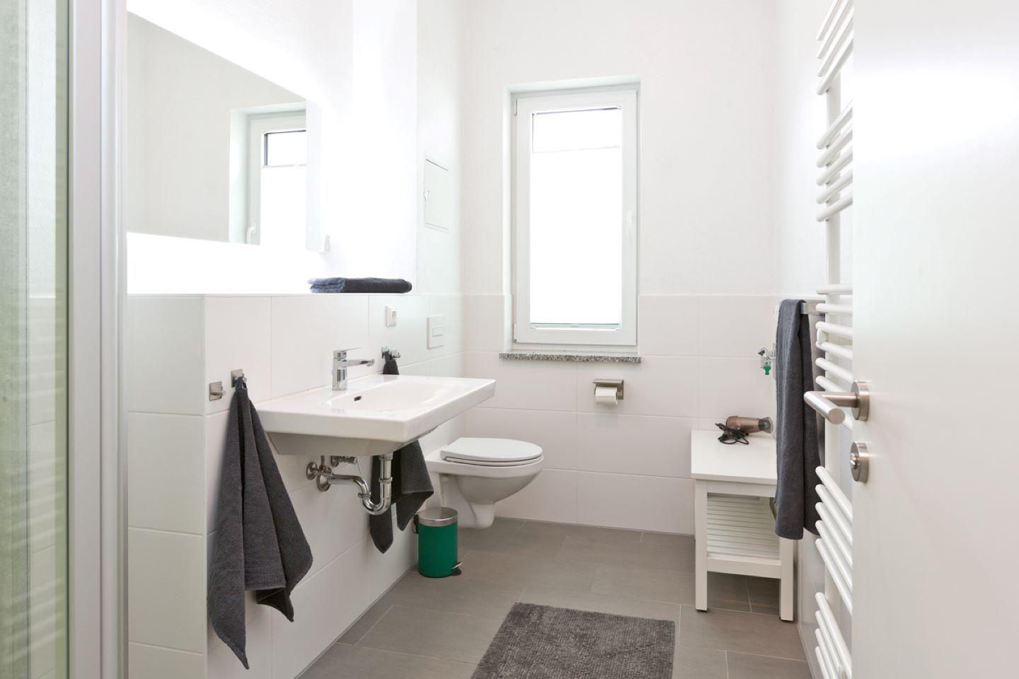 Badezimmer mit Waschbecken, Toilette, Dusche und Heizkörper.