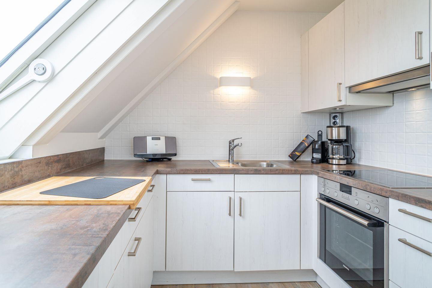 Kitchen with skylight, white cabinets, and stainless steel appliances.