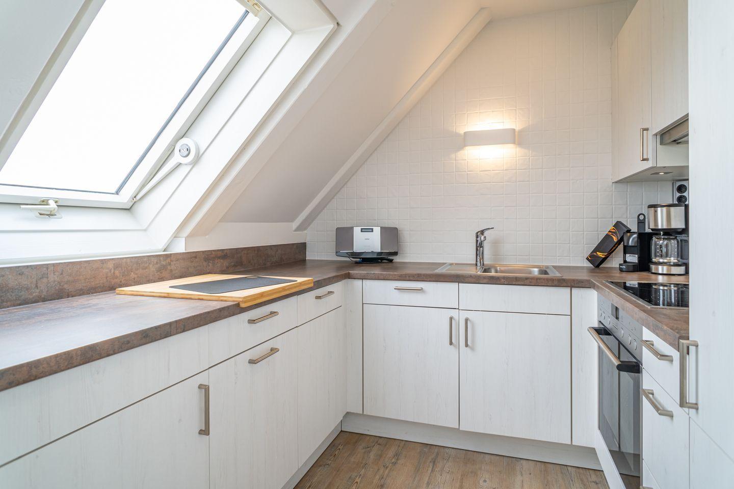 Kitchen with sloped ceiling, window, countertops, and appliances.