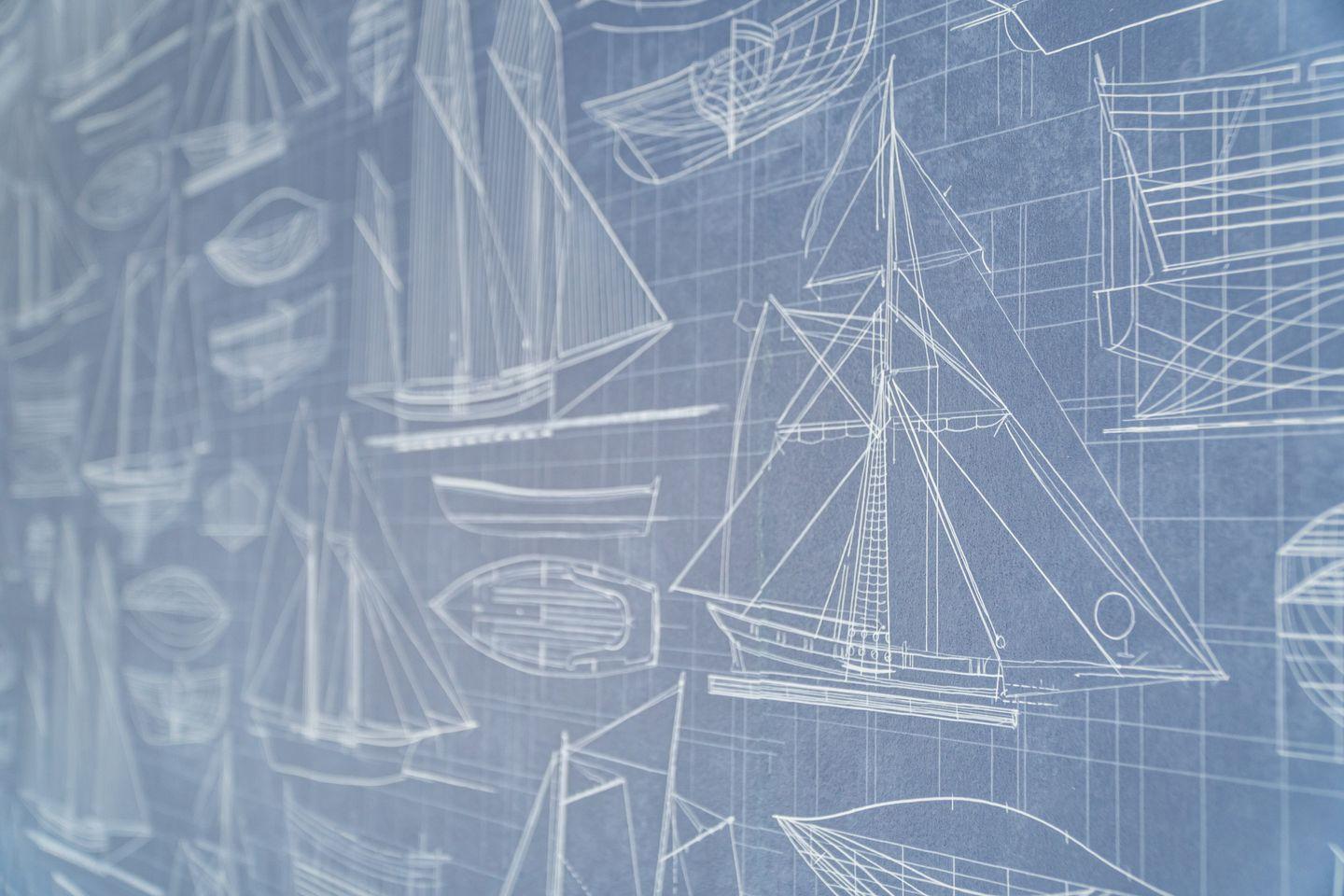 Wall with technical drawings of ships and boats in white on blue background.