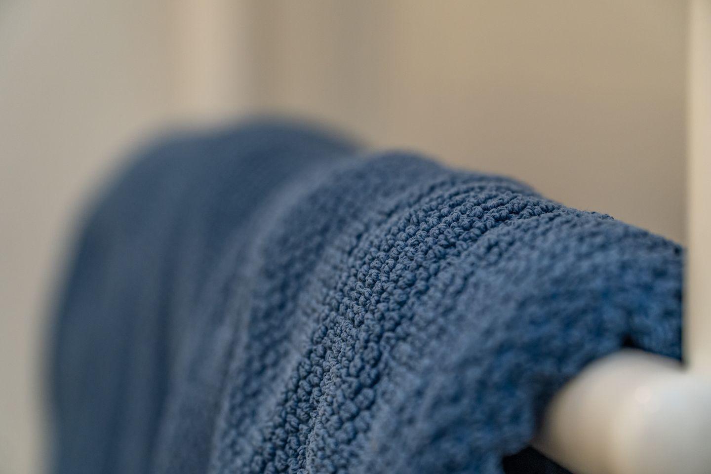 A blue towel on a white towel rack in a bathroom.