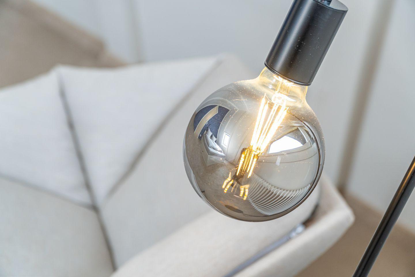 A large bulb with visible filaments reflects the room.