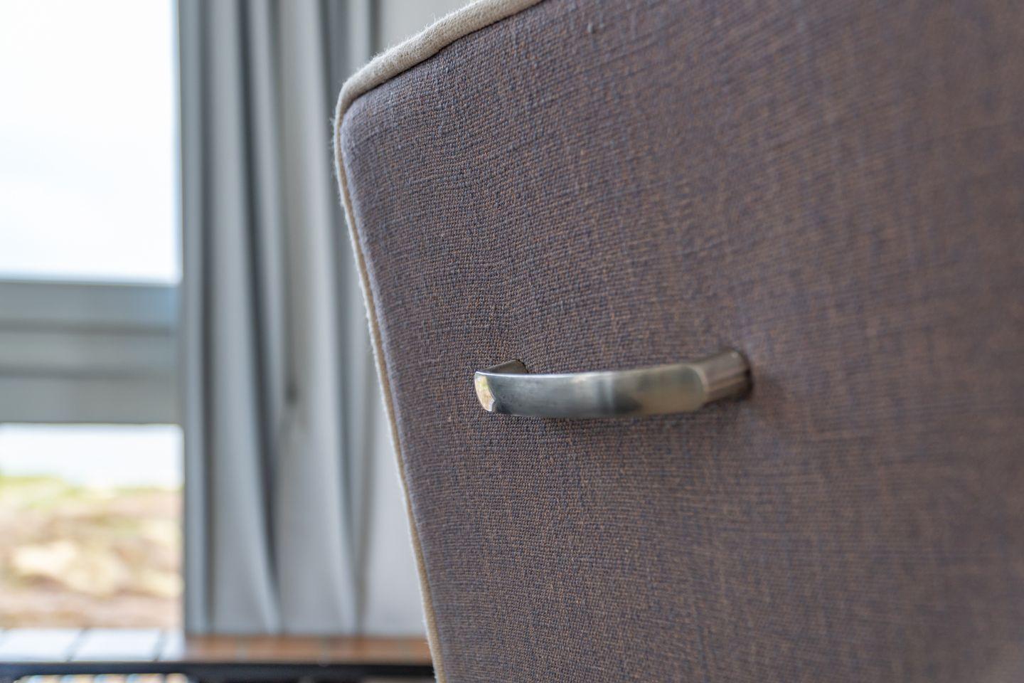 Close-up of a chair with metal handle and fabric upholstery near window