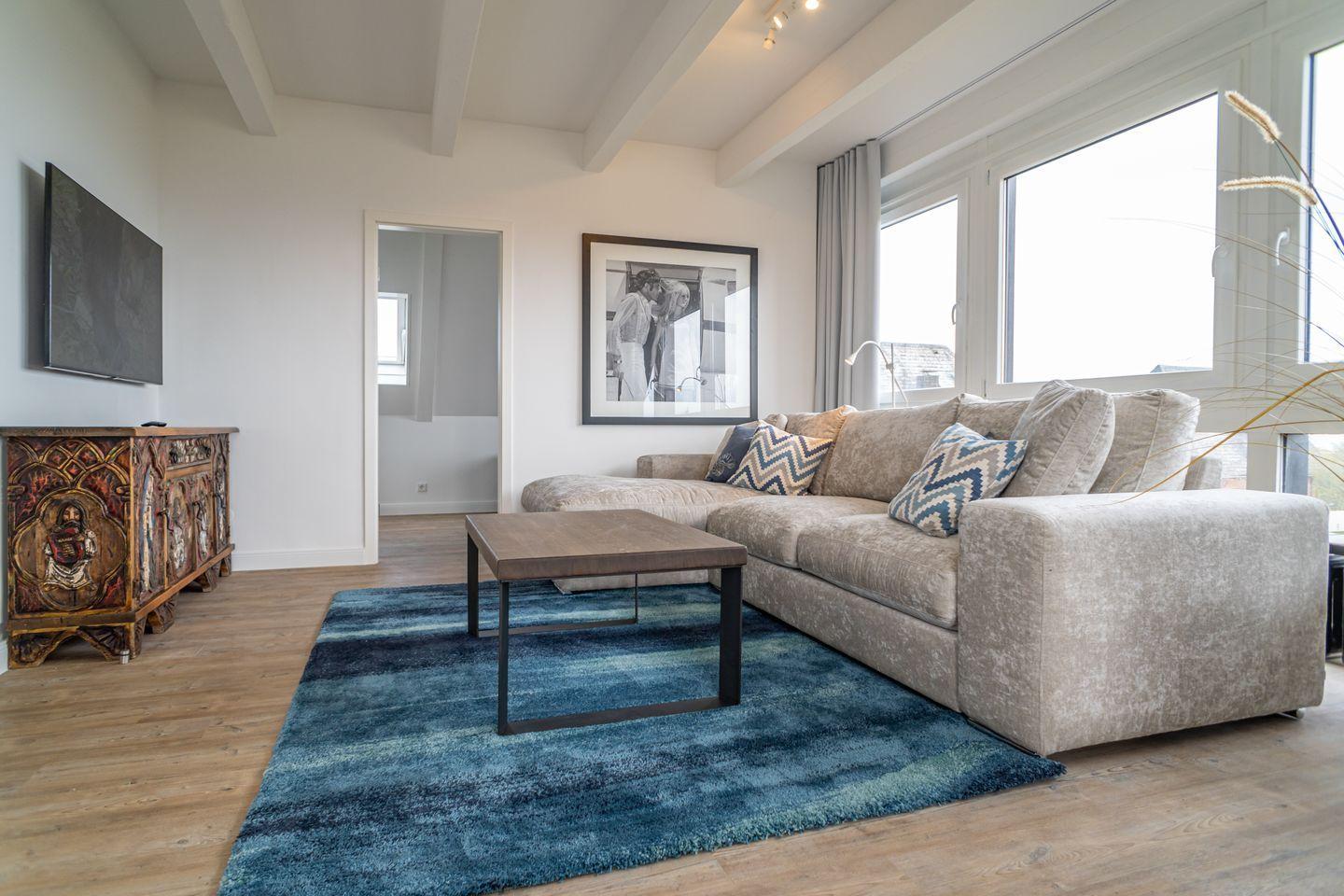 Living room with sofa, rug, and TV mounted on the wall.