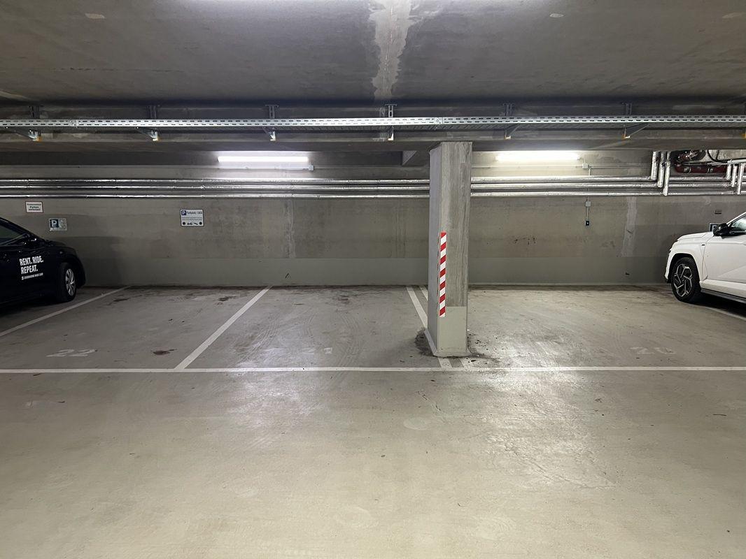 Untertageparkplatz mit zwei geparkten Autos und Betonstützen.