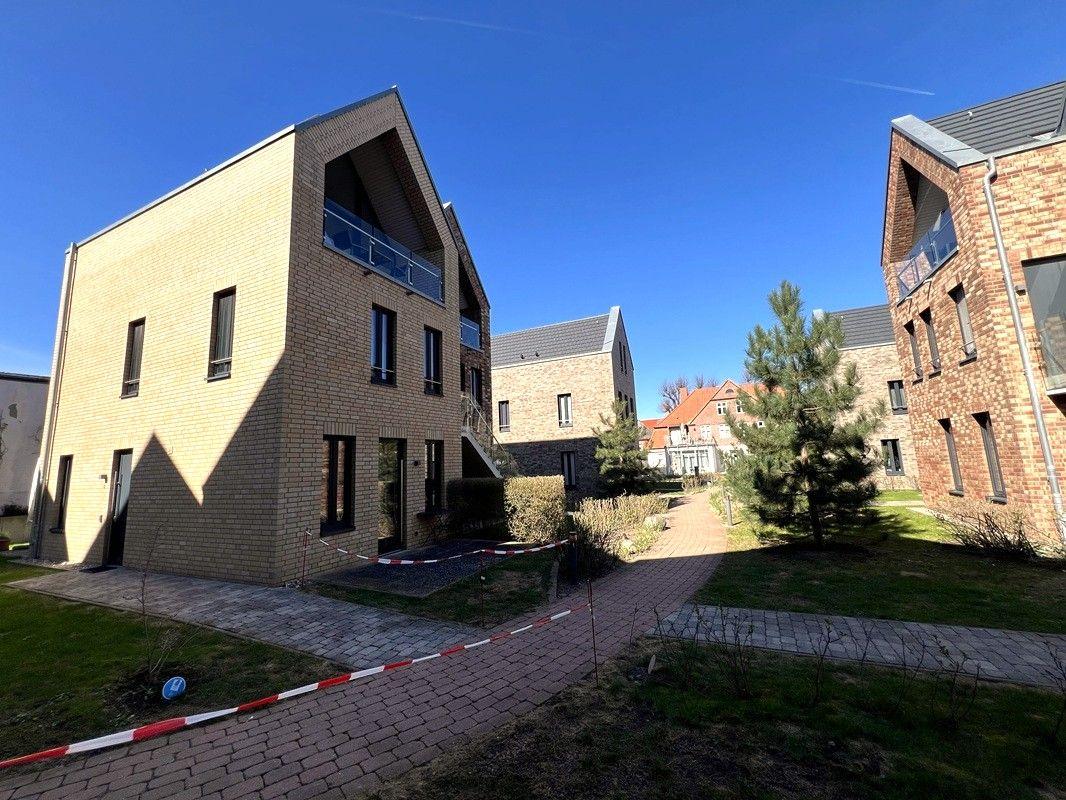 Moderne Wohnhäuser mit Balkonen und gepflasterten Wegen in ruhiger Wohngegend.