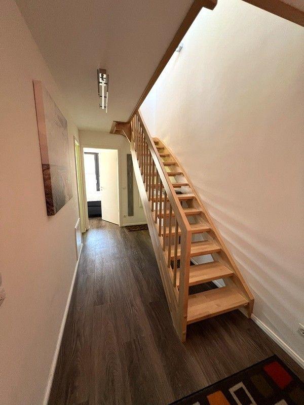 Holztreppe führt zur oberen Etage. Flur mit dunklem Holzboden und Wandbild.