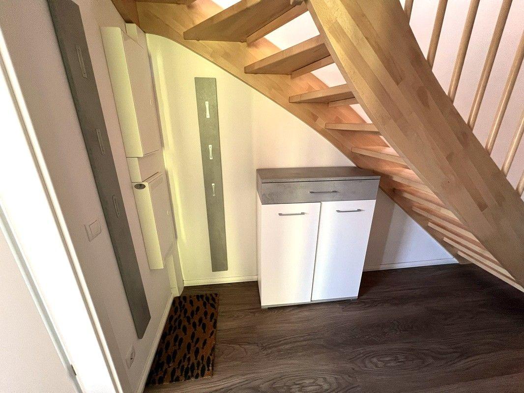 Treppenhaus mit Holztreppen und weißem Schrank unter der Treppe.