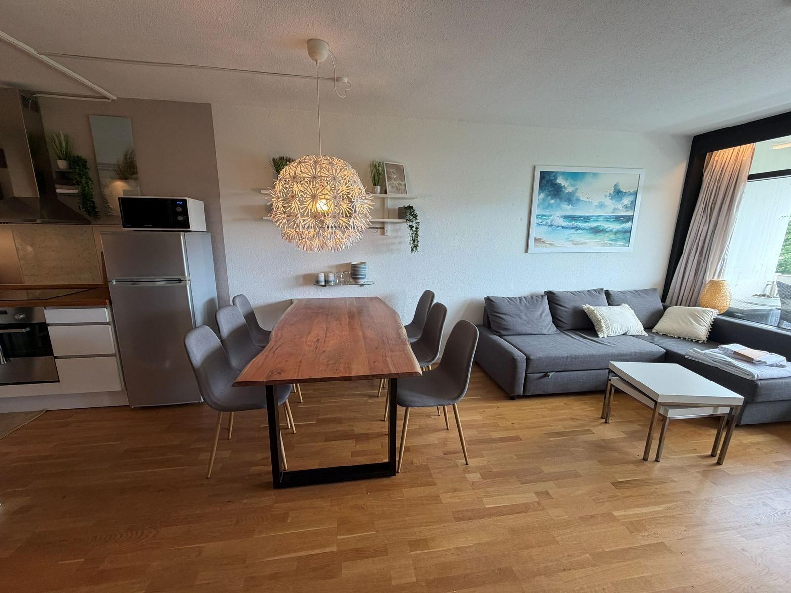 Wohn- und Essbereich mit Sofa, Esstisch und Küchenzeile.