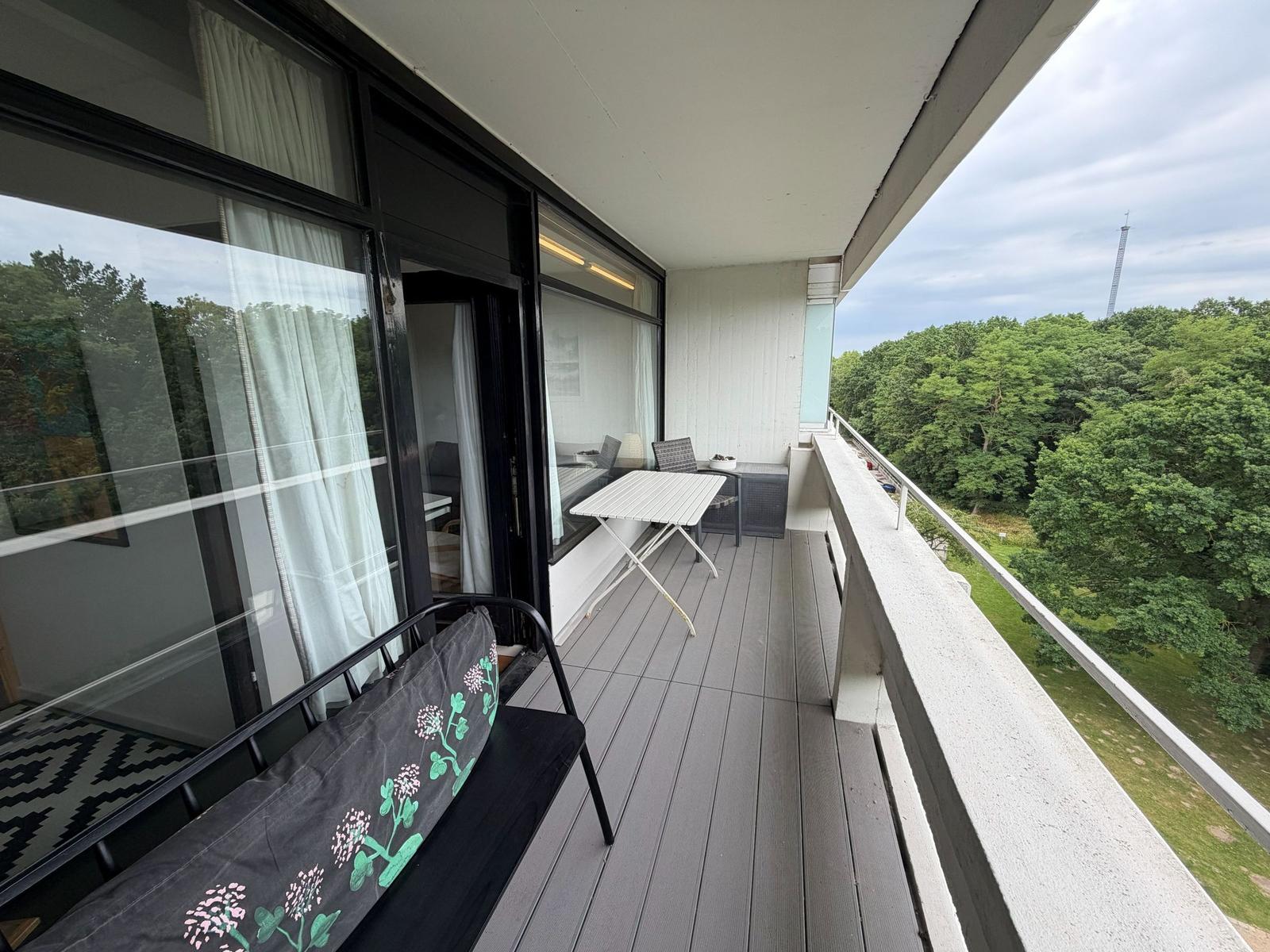 Terrasse mit Tisch, Stühlen und Blick auf Wald.